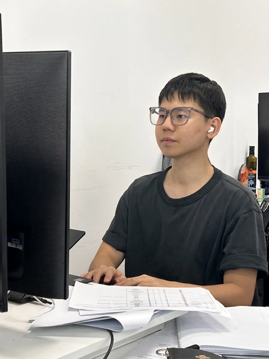 Frank 在辦公桌前工作，螢幕背對鏡頭